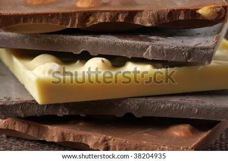 Stack of various chocolate close-up on brown canvas. Shallow DOF.