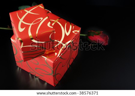Two ornamented red gifts and red rose on black background.