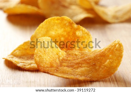 Group of potato chips close-up on wooden surface.