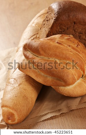 Wheat and rye bread on paper bag on wooden surface.