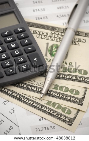 Close-up of calculator, pen and dollars on financial table.