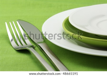 stock photo White and green plates stainless fork and knife on green 