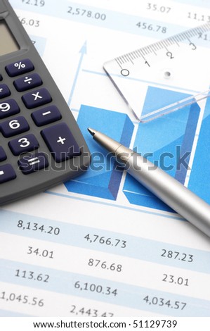 Close-up of calculator, pen and rule on paper table with graph.