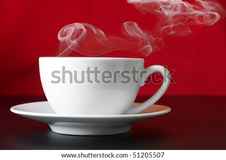 White cup of coffee with steam on red/black background.