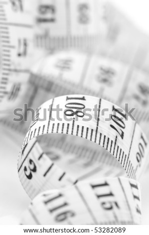 Close-up of unwound white tape measure with black scale.