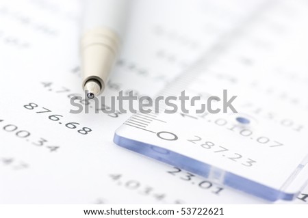 Close-up of silver pen and plastic rule on paper table numbers.