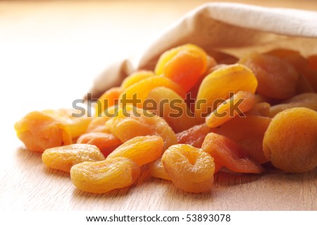 Heap of dried apricots spill out canvas bag.