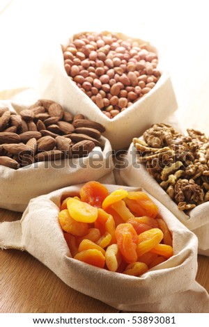 Heap of nuts and dried apricots in canvas bags. Focus on apricots.