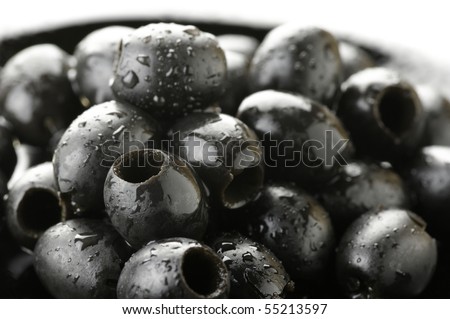 Heap of wet black olives in black plate on white background.