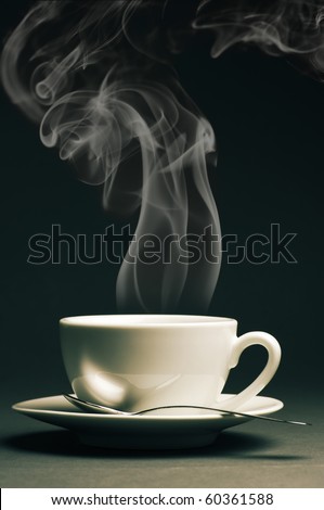Cup of hot coffee with steam on dark background. Toned image.
