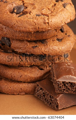 Stack of chocolate cookies and pieces of porous chocolate close-up.