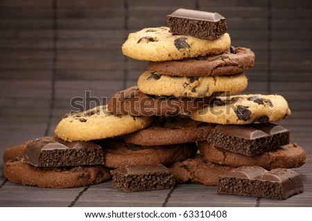 Stack of chocolate cookies and pieces of porous chocolate on brown mat.