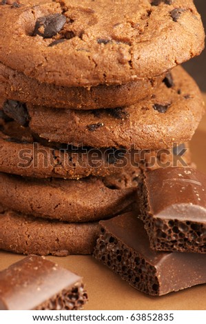 Stack of chocolate cookies and pieces of porous chocolate close-up.