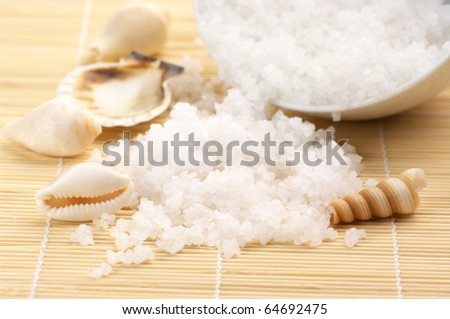 Natural salt of Dead Sea spilling from white bowl on mat.