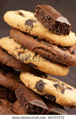 Stack of chocolate cookies and pieces of porous chocolate close-up on brown mat.