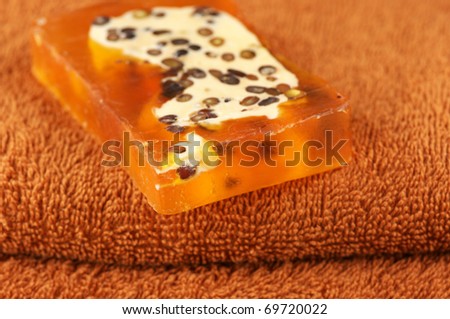 Bar of natural handmade soap with scrub on brown towel.