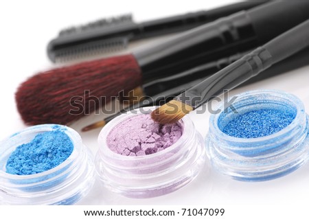 Set of powder eye shadows in jars and brushes close-up.