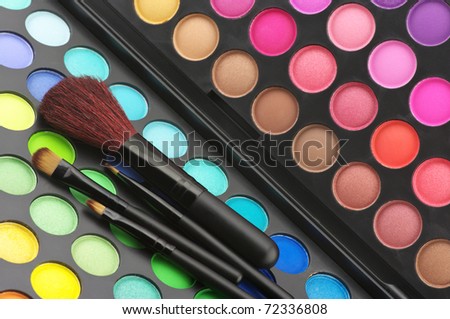 Set of make-up brushes on colorful eye shadows palette.