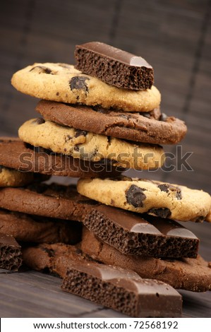 Stack of chocolate cookies and pieces of porous chocolate on brown mat.