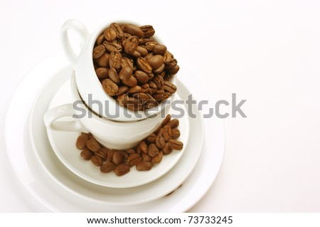 Roasted coffee beans in white cups on light background.