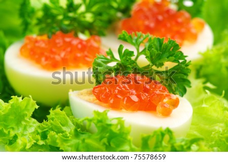 Close-up of canapes with egg, salmon caviar and parsley on lettuce leaves.