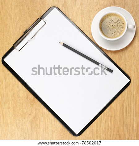 Clipboard with blank page and cup of coffee on wooden desk. View from above.
