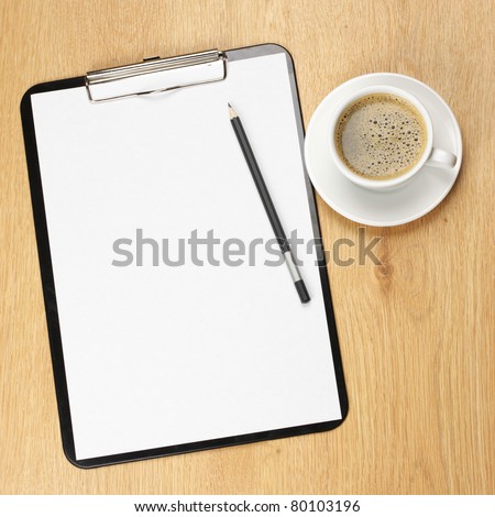Clipboard with blank page and cup of coffee on wooden desk. View from above.