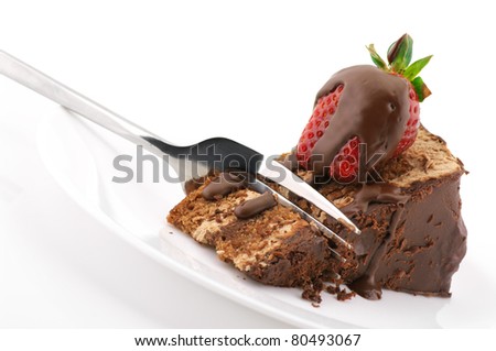 Slice of chocolate cake with strawberry and fork in white plate on white background.