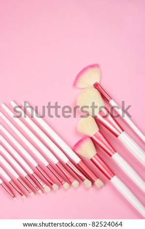 Set of white-pink make-up brushes on pink background.
