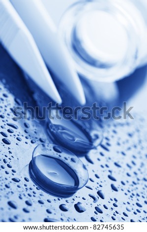 Close-up of two contact lenses, glass bottle and tweezers. Toned image.