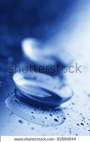 Close-up of two contact lenses with drops. Blue toned image.