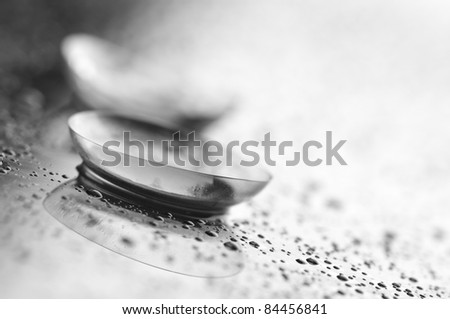 Close-up of two contact lenses with drops on light background.