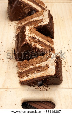 Pieces of chocolate cake lying in row on wooden board.