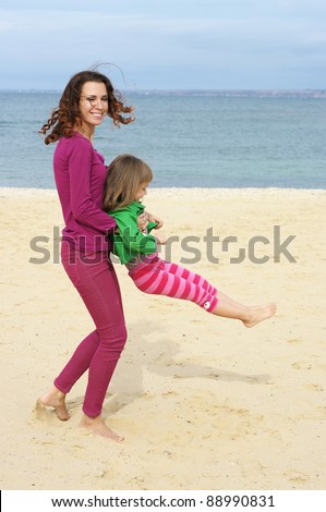 Happy mother and daughter playing at beach.