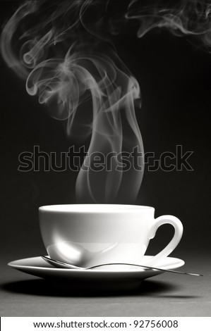 Cup of hot coffee with steam on dark background. Monochrome image.