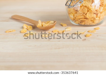 cereal cornflakes in the glass jar and spilling out to the wood table