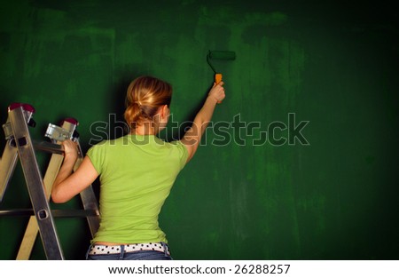 A woman painting a wall roller, standing on the stairs, painted green