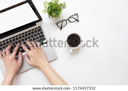 Man typing on laptop computer with white blank screen over white office desk table with cup of coffee. Top view with copy space, flat lay.