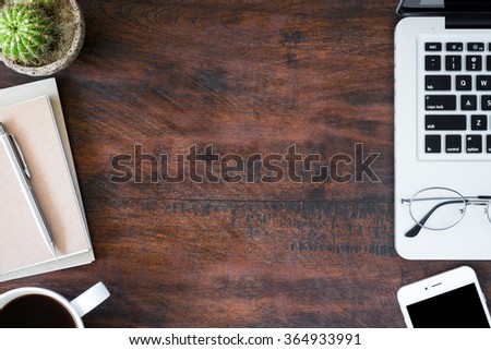 Hipster vintage office desk table with laptop, smartphone, eye glasses, notebooks, pen and a cup of coffee. Top view with copy space.