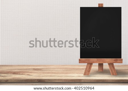 Clean blackboard with easel on top of wooden table with grey wall background. For the idea, you can put the menu text on the blackboard with your products aside on the table.