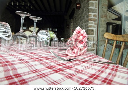 Glasses, fork and knife on red and white checked gingham tablecloth