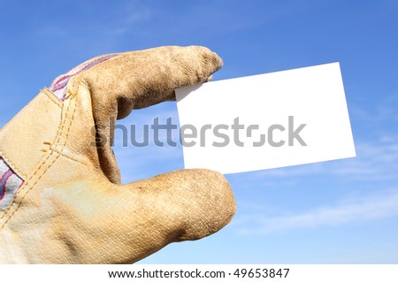 Worker Wearing Leather Work Glove Holding a Blank Business Card Against a Blue Sky