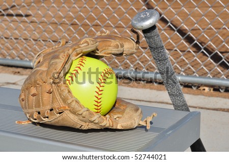 Yellow Softball, Bat, and Glove on an Aluminum Bench