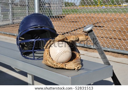White Softball, Helmet, Bat, and Glove on an Aluminum Bench