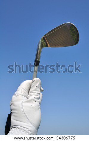 Golfer Wearing a Golf Glove Holding an Iron (Golf Club) Against a Blue Sky