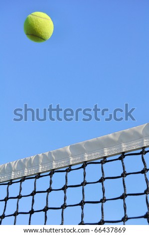Yellow Tennis Ball Flying Over the Net Against a Clear Blue Sky