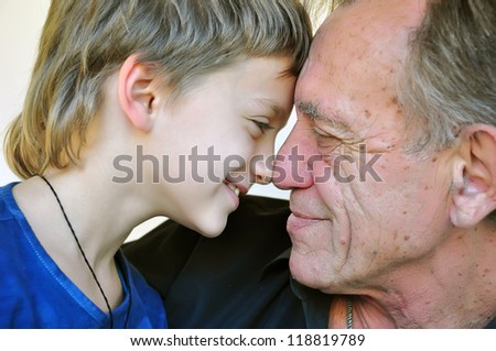 family portrait: father at his 60s and his youngest 8 years old son touching noses and having fun
