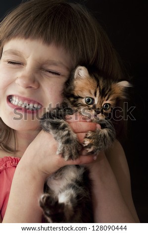 child hugging a young kitten