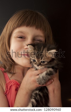 child hugging a small striped kitten
