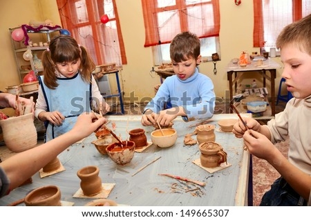 young children decorating their handmade clay pottery